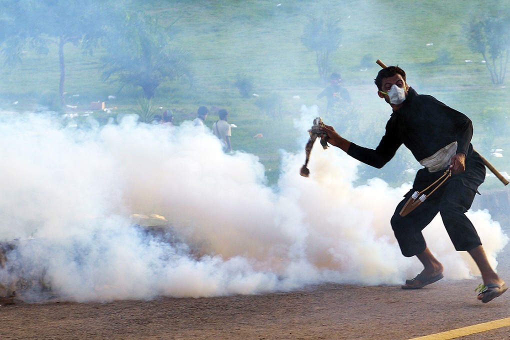 A Pakistani supporter of populist cleric Tahir ul-Qadri returns a tear gas shell towards riot police during an anti-government protest in Islamabad. Photo: AFP