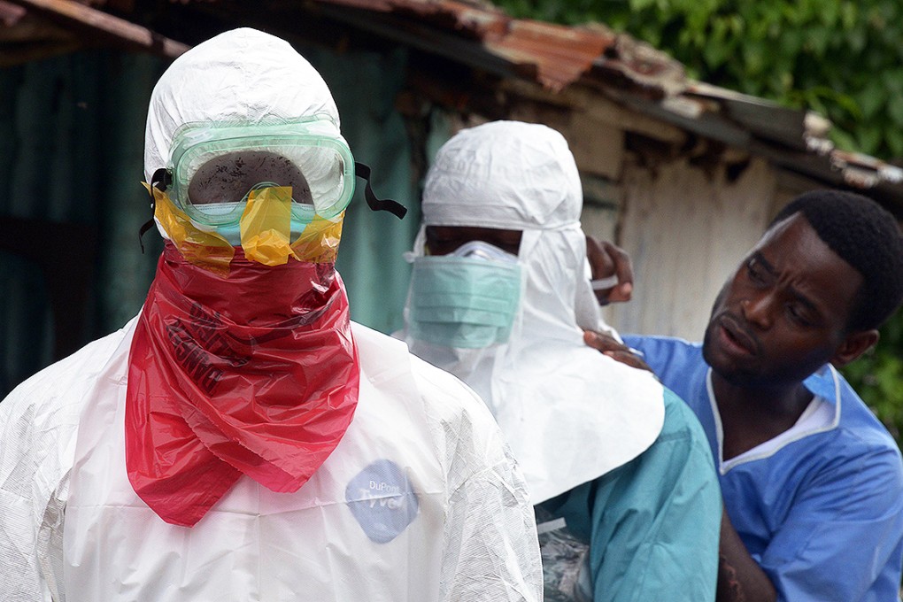 Medical workers of the John Fitzgerald Kennedy hospital in Monrovia put on protective suits prior to carrying bodies of Ebola virus victims. Photo: EPA