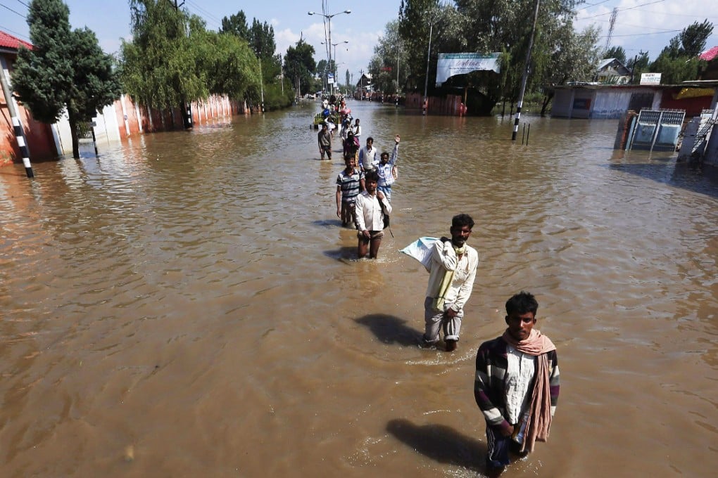 People wade through a flooded street as they move toward higher ground in Srinagar. Photo: Reuters