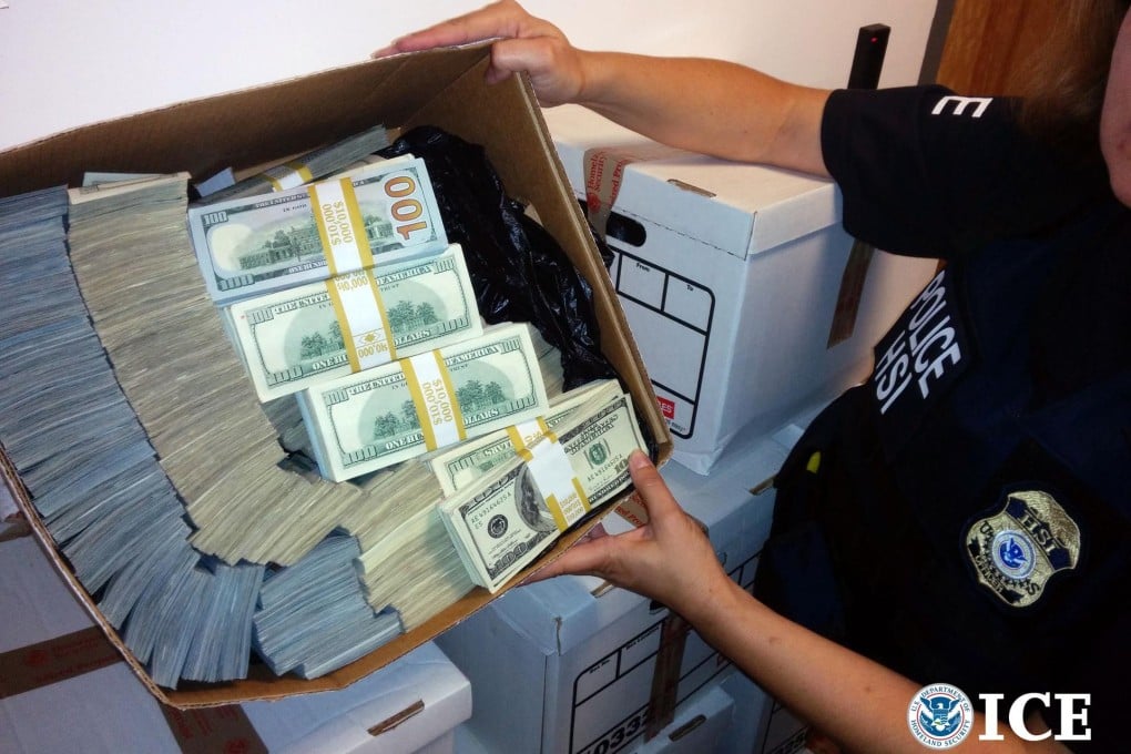 A police officer with some of the US$65 million in cash seized in Wednesday's raids. Photo: AFP/ICE