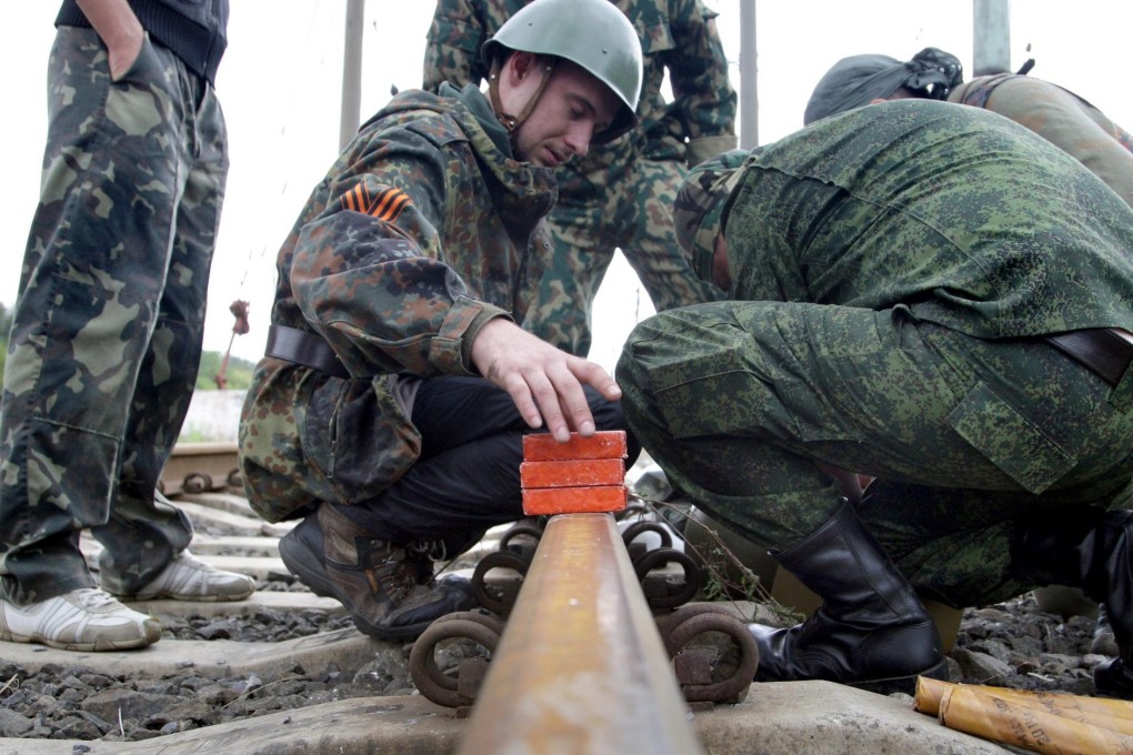 Pro-Russia rebels defuse a shell on a railway in Ilovaisk. Photo: EPA