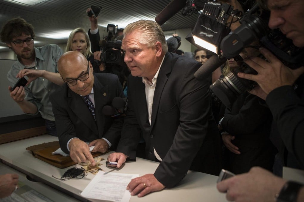 Doug Ford (centre) submits his papers for the mayoral race after his brother Rob's pull-out. Photo: AP