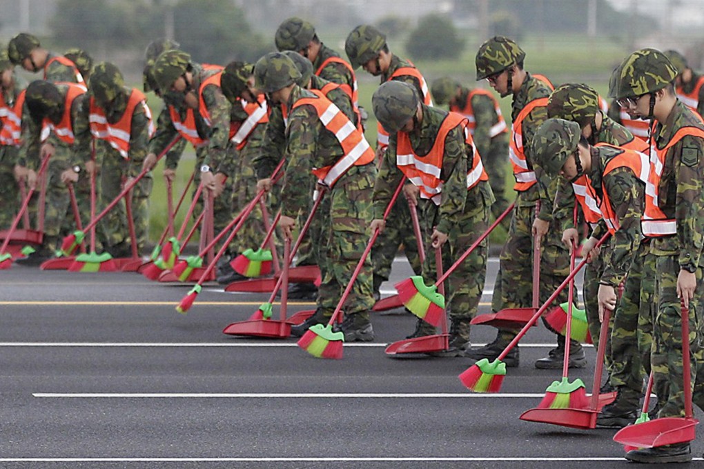 Soldiers in Chiayi county sweep a highway yesterday ahead a landing by military aircraft as part of a drill. Photo: Reuters