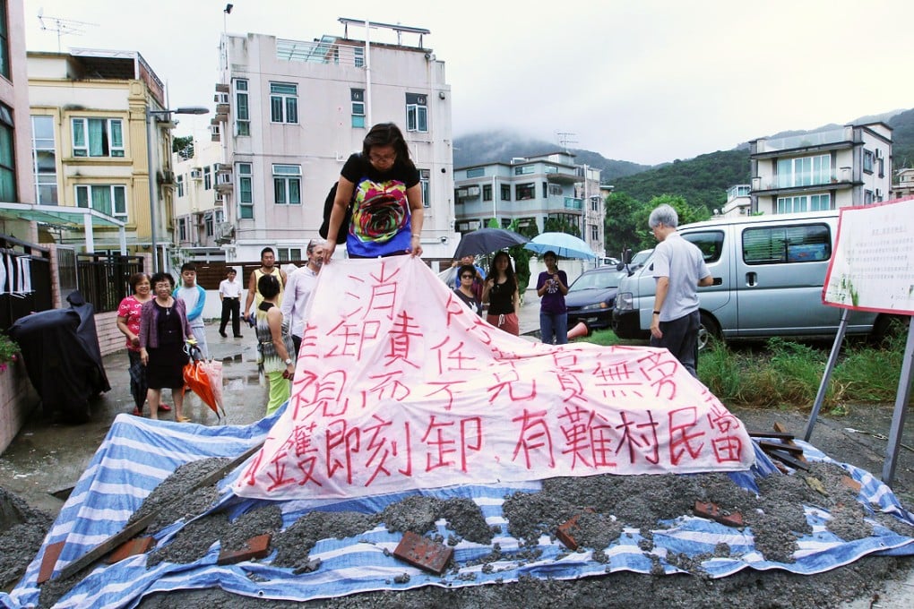 Ho Chung New Village residents protest in front of a cement barrier yesterday. Photo: Edward Wong
