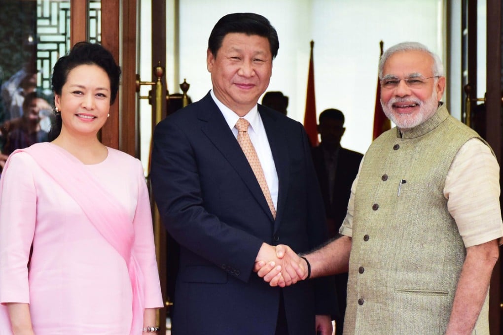 China's President Xi Jinping (centre) and Indian Prime Minister Narendra Modi (right) shake hands as Xi's wife Peng Liyuan (left) looks on as they arrive in Ahmedabad. Photo: AFP