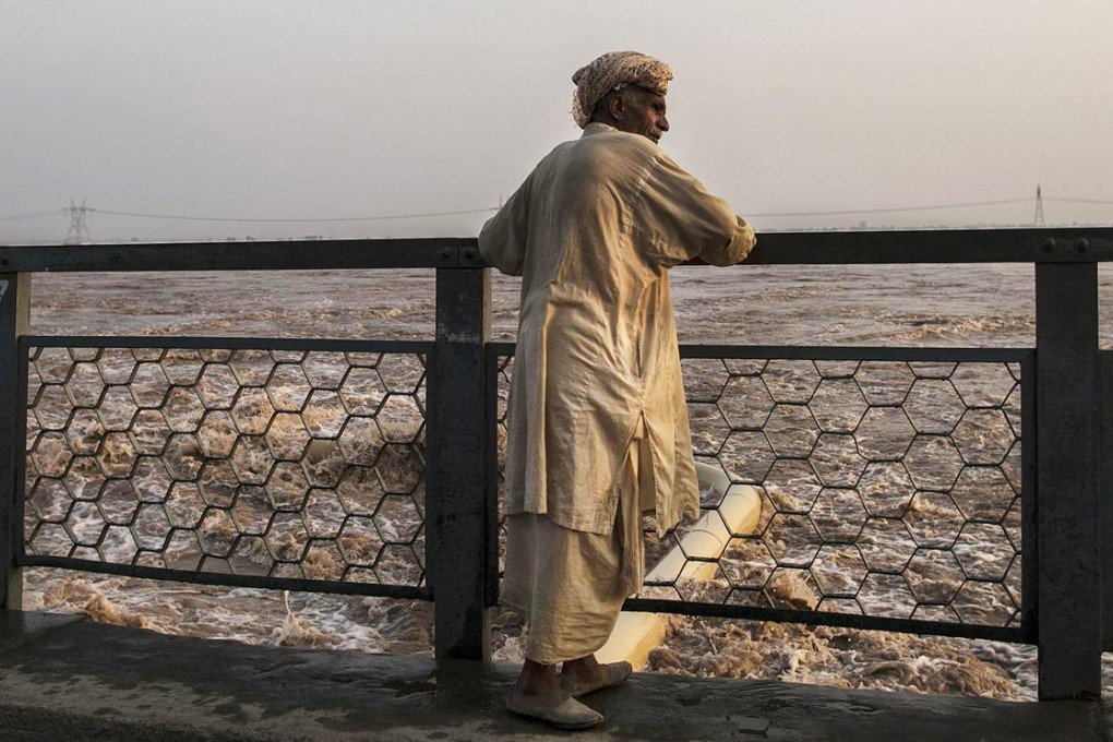A man watches as water discharges from a dam in Jhang, Punjab province, following heavy rain. Photo: Reuters