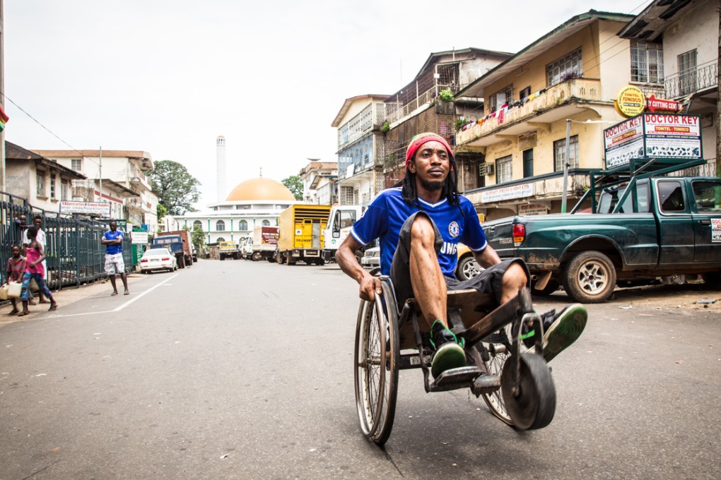 A man travels along a street in his wheelchair as the three-day lockdown to prevent the spread on the Ebola virus in Freetown, Sierra Leone comes to an end on Sunday. Photo: AP