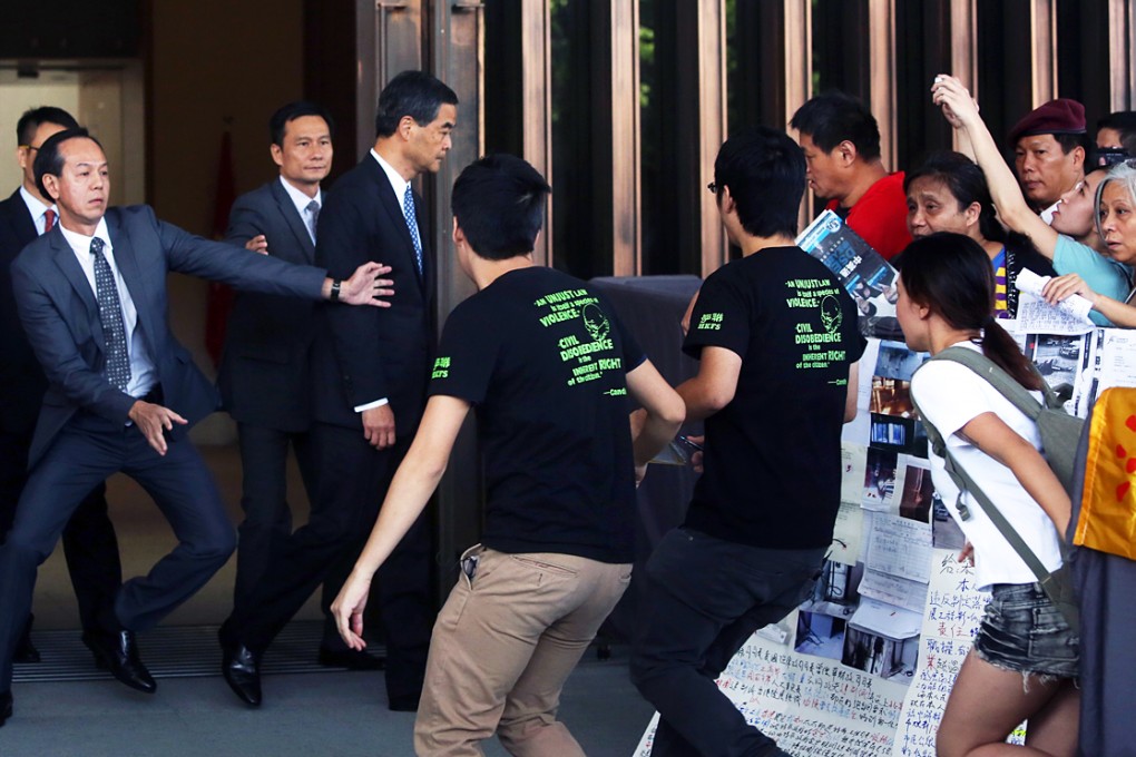 A security officer puts out a protective arm as about a dozen of the students who moved their class boycott to Tamar yesterday rush towards Leung Chun-ying. Photo: Sam Tsang