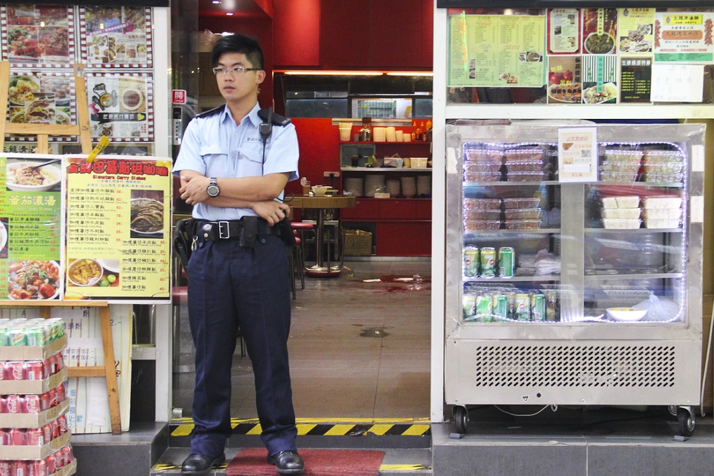 A policeman stands guard outside the tea cafe on Portland Street, Mong Kok, where Tsang Wing-ho, 42, was killed. Photo: SCMP Pictures