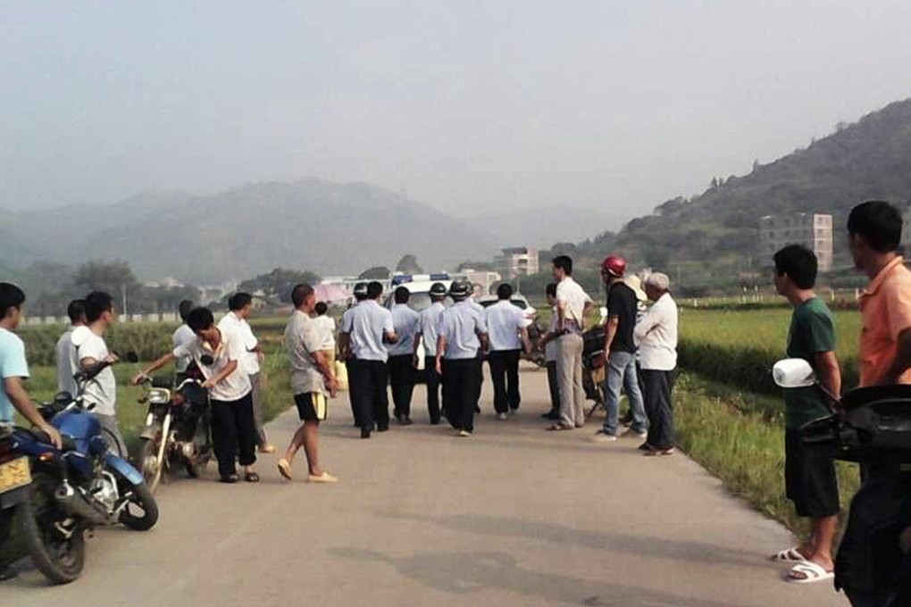Policemen walk on a country road where a fatal knife attack on four schoolchildren occurred on September 26, 2014 in Lingshan, Guangxi. Photo: Weibo