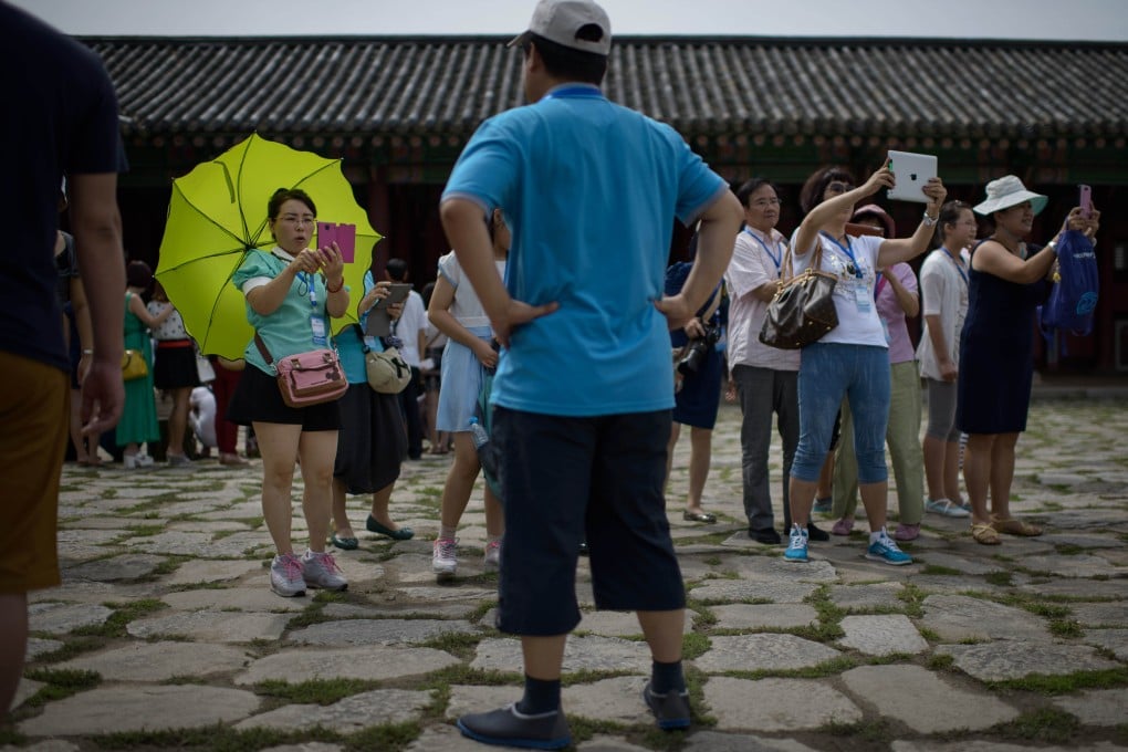 Tourists from China take photos before the Gyeongbokgung Palace in Seoul. Photo: AFP