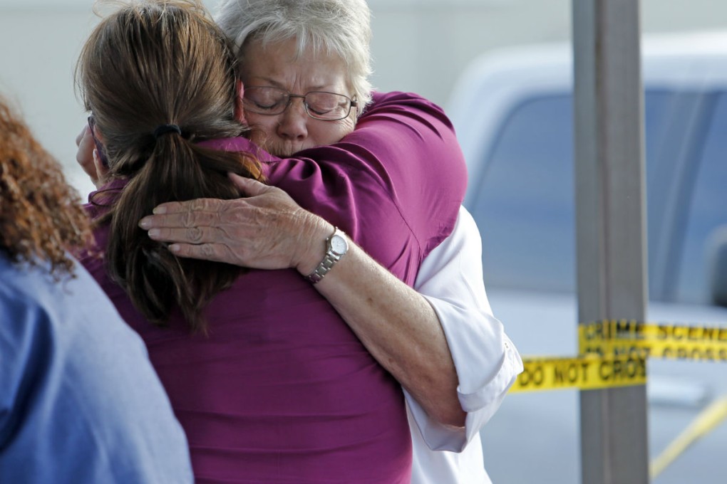 Employees and friends wait behind a tape for word of loved ones as police investigate. Photo: AP