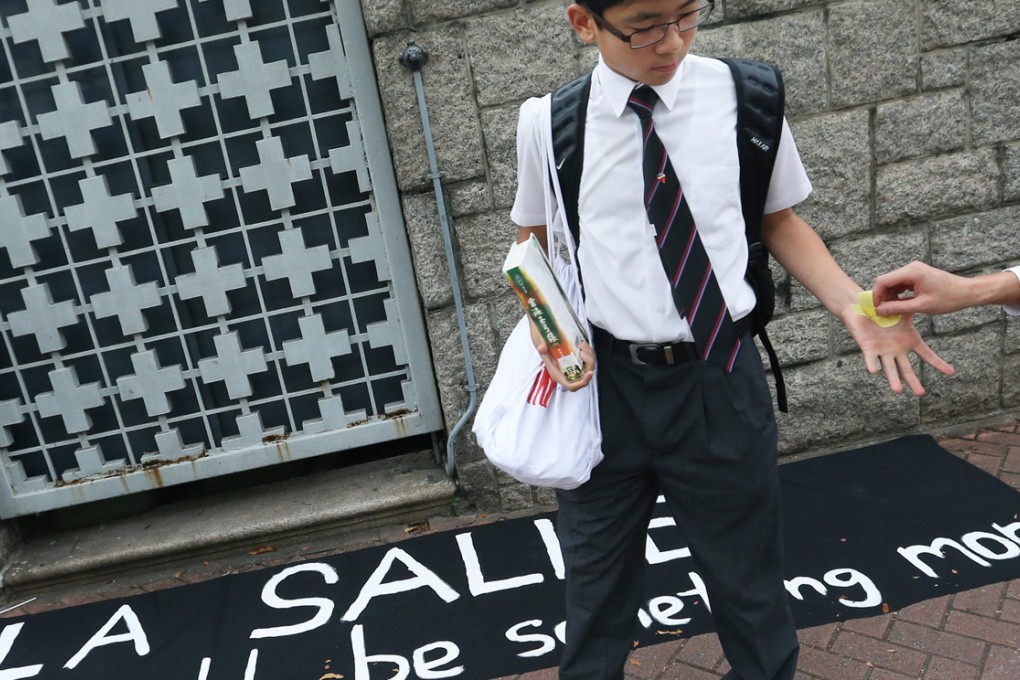 A pupil receives a yellow ribbon representing support for democracy outside La Salle College in Kowloon. Photo: K. Y. Cheng