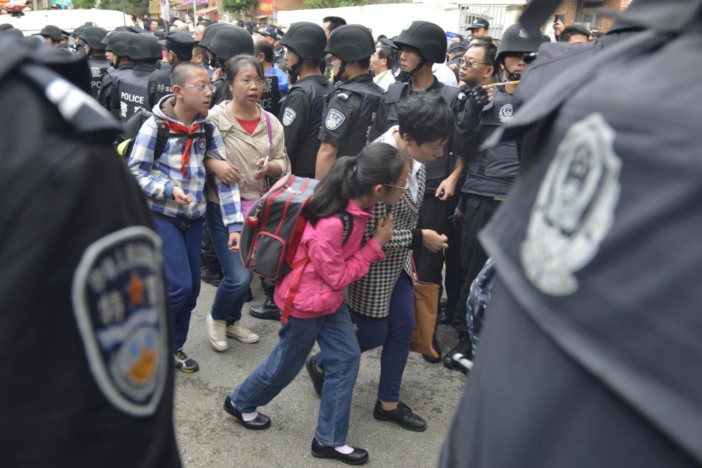 Police stand guard as parents take their children home after a deadly stampede at a primary school in Kunming . Photo: AFP