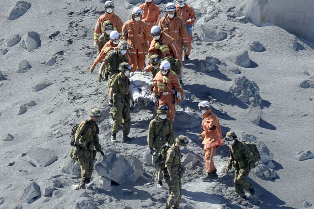Soldiers and firefighters carry an injured hiker near the crater of Mount Ontake. Photo: Reuters