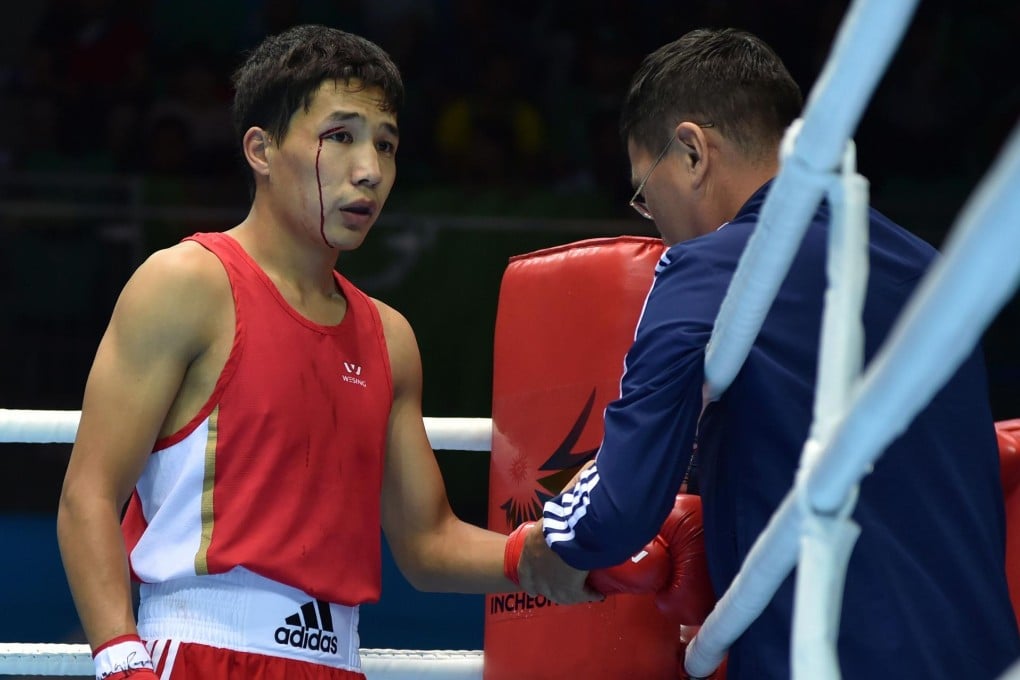 Boxer Azat Usenaliev of Kazahkstan gets treatment for a gash after an accidental clash with his opponent in the flyweight class. Usenaliev lost his bout in a TKO. Photo: AFP