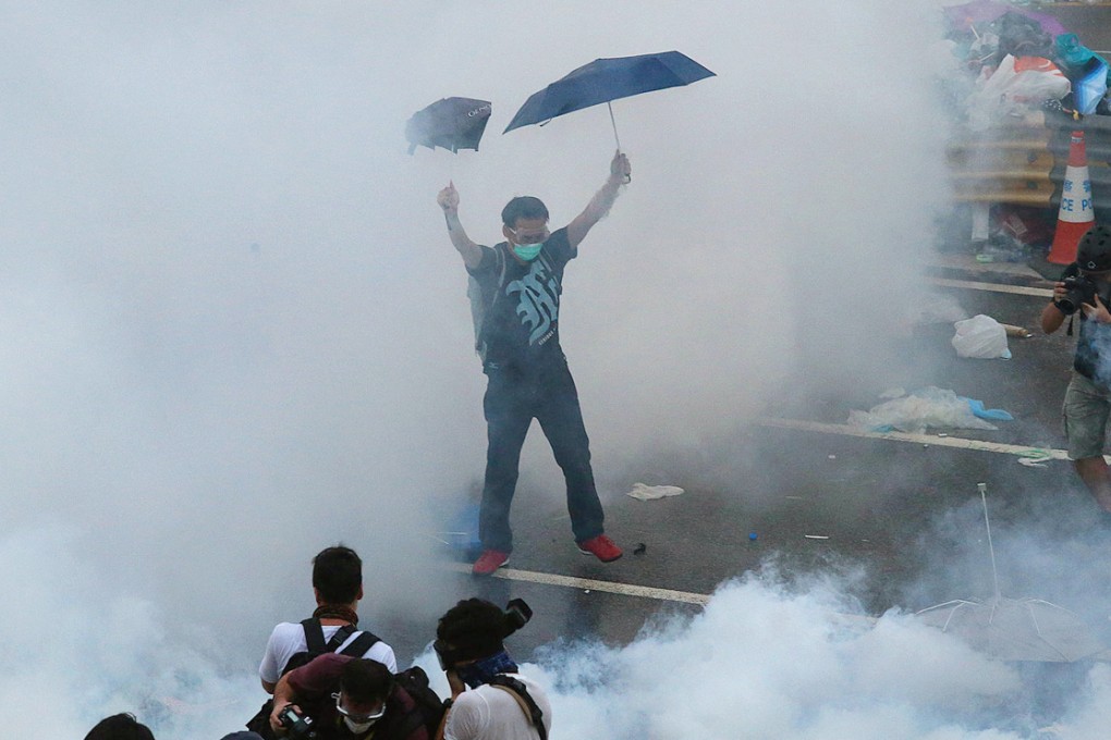 Enveloped by clouds of tear gas smoke, a protester strikes a defiant pose during yesterday's stand-off near the government headquarters in Admiralty. Photo: K.Y. Cheng