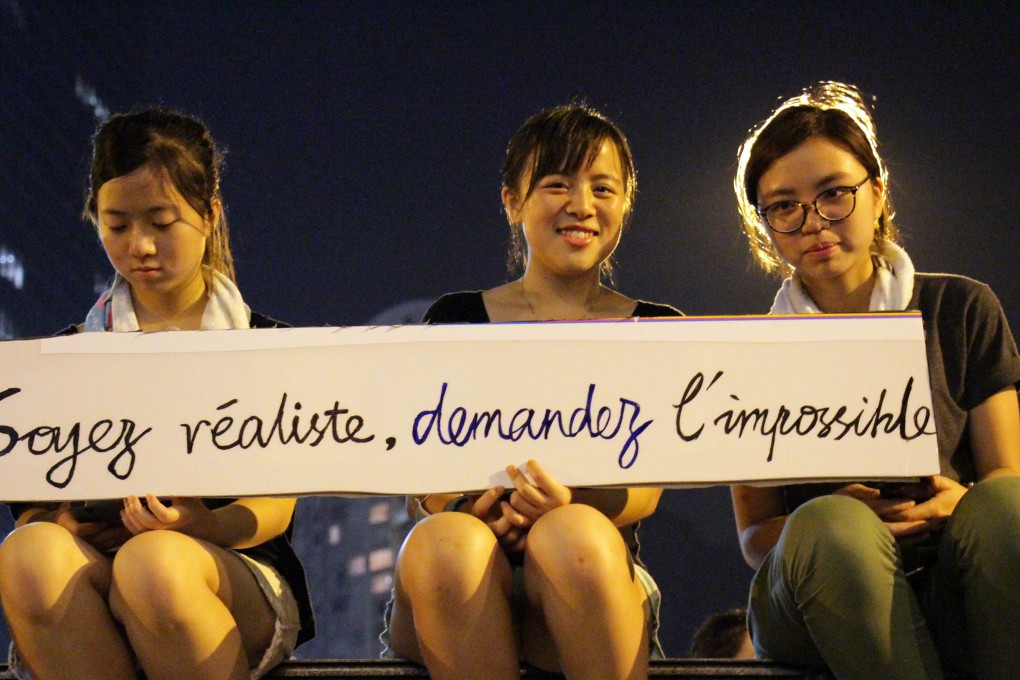 Three students holding a banner that reads "Soyez réaliste, demandez l'impossible" (Be realistic, demand the impossible), a slogan from the Mai 1968 student movement in France, during pro-democracy demonstrations in Hong Kong on Monday. Photo: AFP
