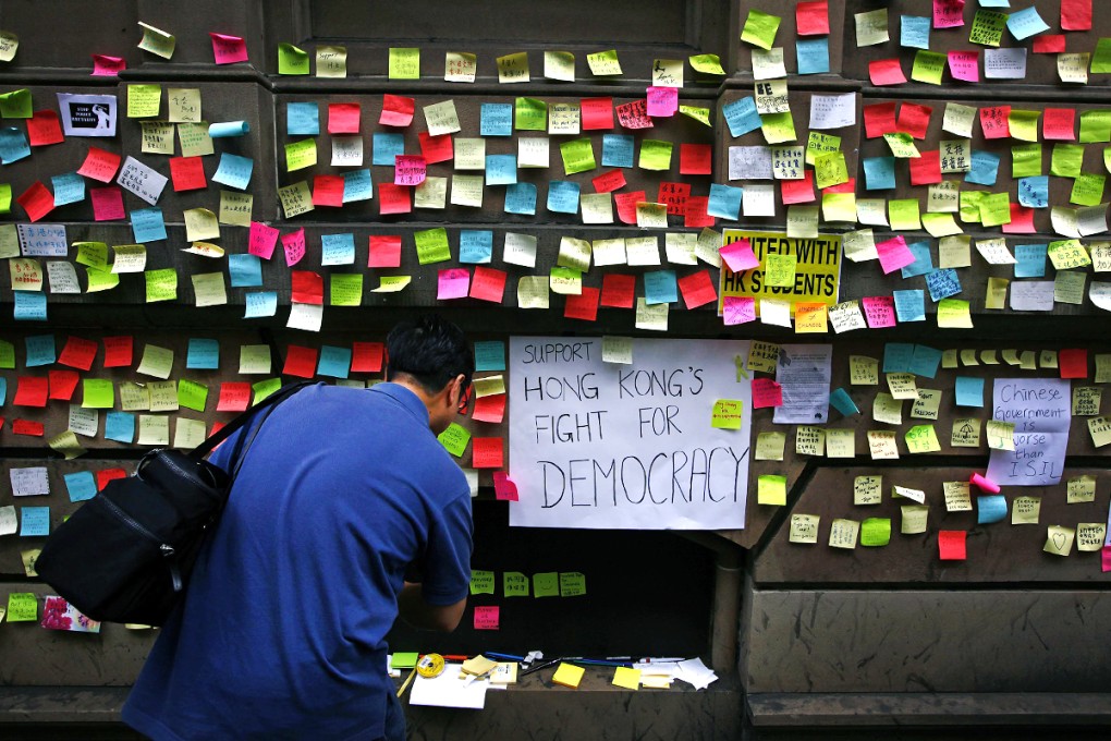 A man writes a message of support for pro-democracy protesters in Hong Kong, on the wall of Hong Kong House in central Sydney. Photo: Reuters