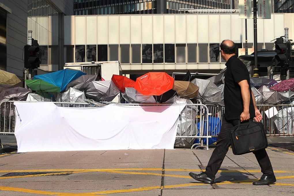 Umbrellas are placed on the road behind a barrier by Occupy Central protesters to block off traffic in Central. Photo: David Wong