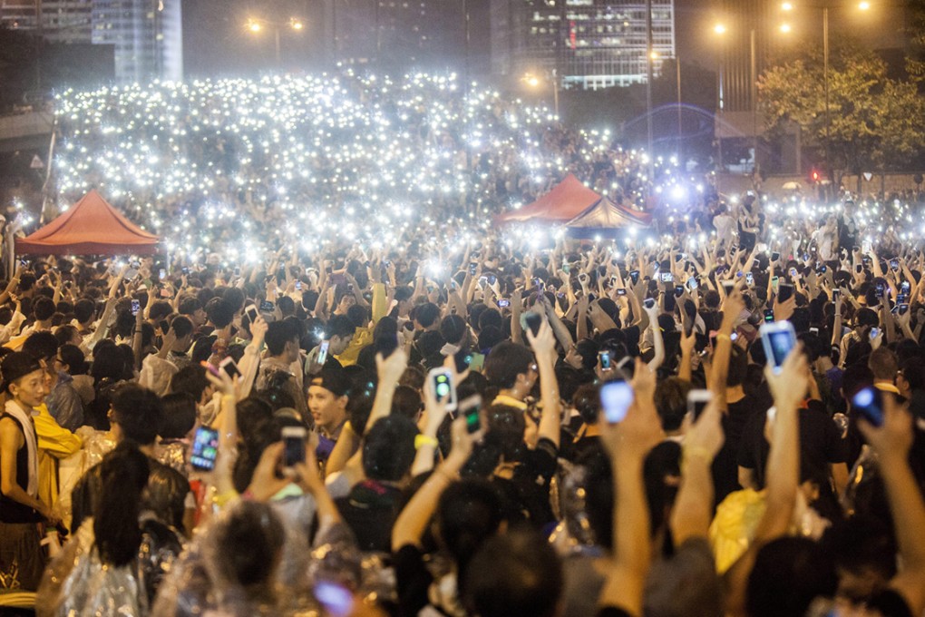 Occupy Central protesters hold up their mobile phones as lights in front of the Hong Kong government offices. Photo: EPA