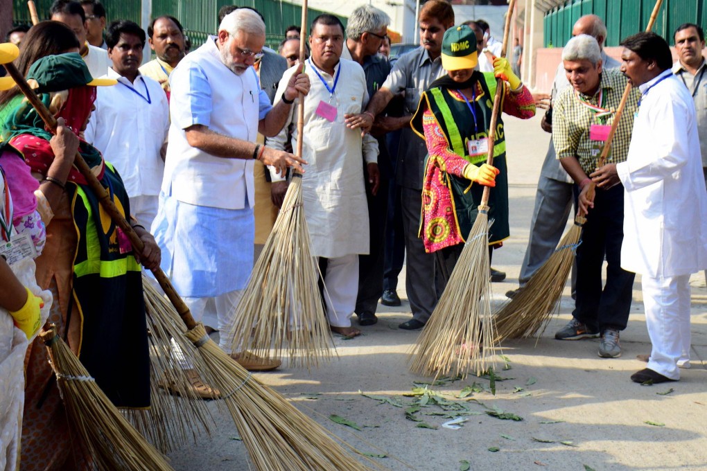 Prime Minister Narendra Modi (left) sweeps a street in a poor area of New Delhi yesterday as part of the national clean-up. Photo: AFP