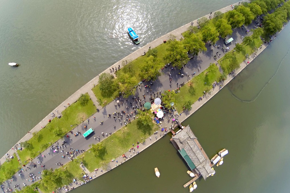 Tourists walk leisurely on a walkway to Broken Bridge, on Hangzhou's West Lake, on the first day of golden week. Photo: Imaginechina