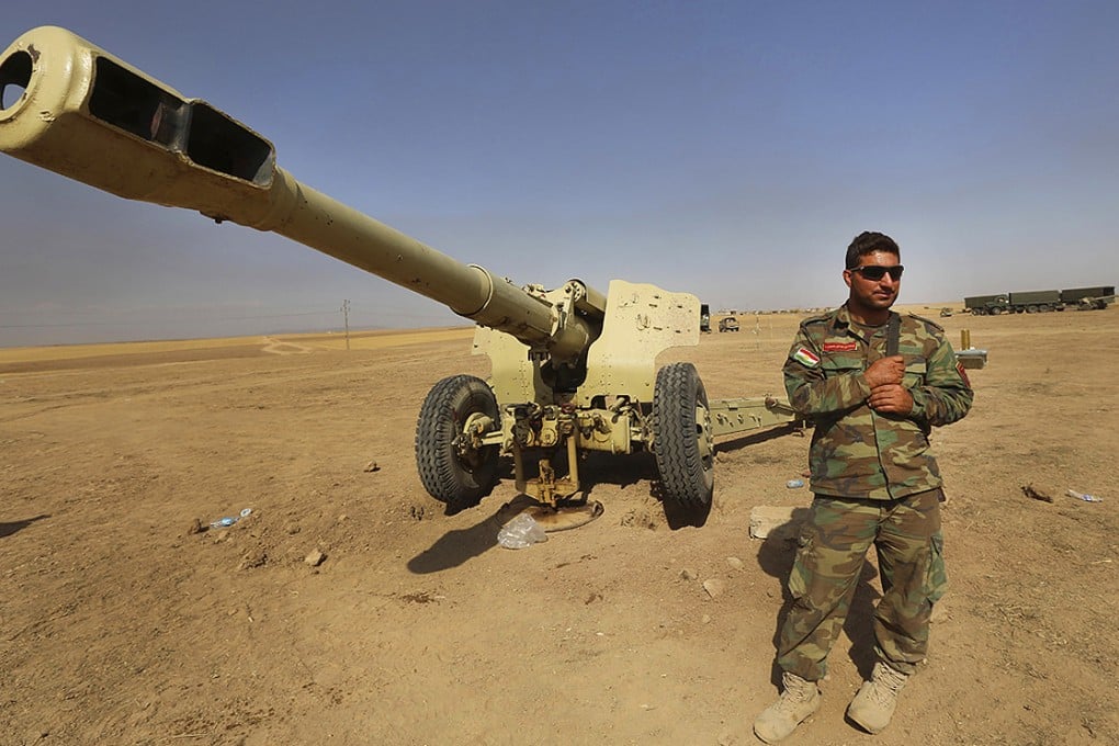A Kurdish peshmerga fighter stands next to an outdated cannon in Mahmoudiyah, Iraq on Wednesday. Photo: AP