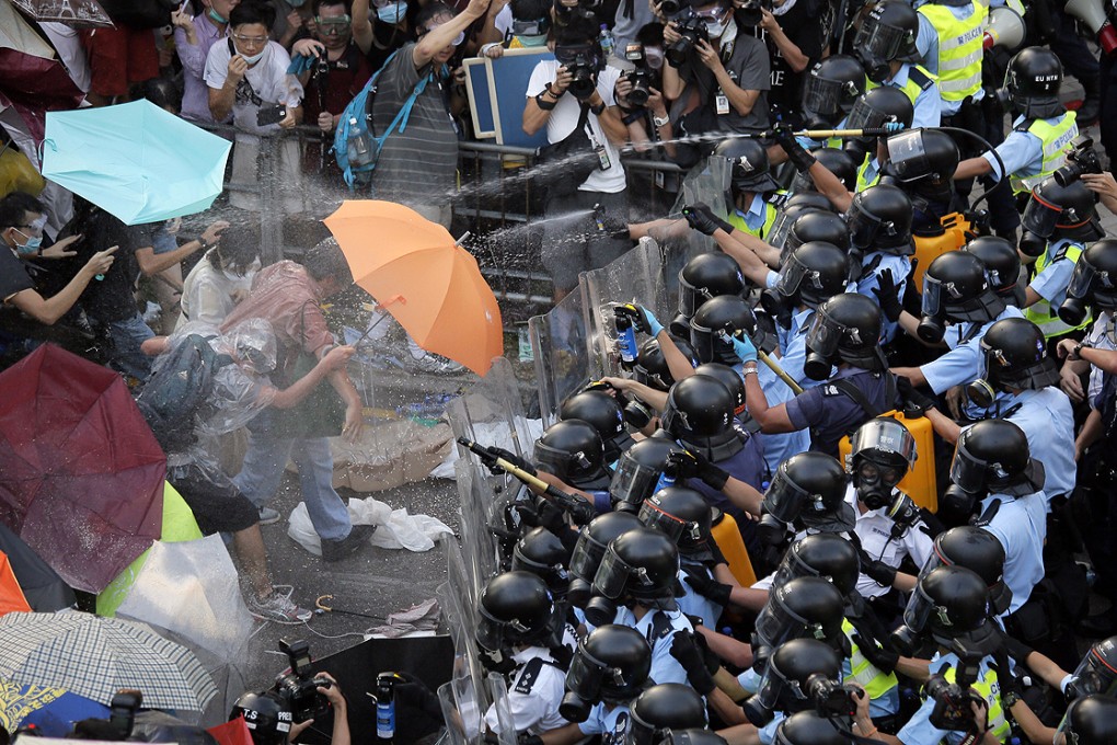 Police use pepper spray against protesters outside government headquarters in Hong Kong on Sunday. Photo: Vincent Yu
