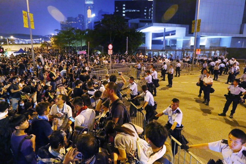 Hundreds of young protesters sit, sleep or stand outside the Chief Executive's office in Admiralty as policemen stand guard behind barriers. Photo: Felix Wong
