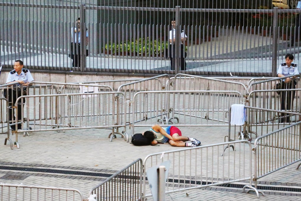 A protester gets some sleep under the watchful gaze of policemen at government headquarters in Admiralty. Photo: Felix Wong