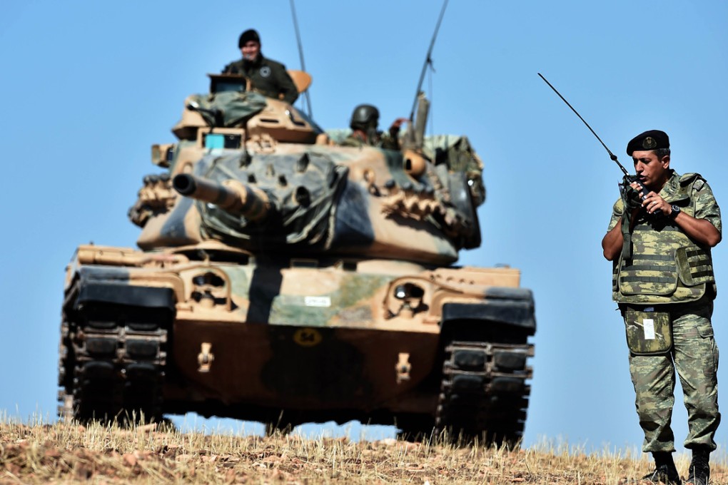 An officer speaks on the radio as Turkish tanks line up on a hill outside the village of Mursitpinar next to Kobane. A female suicide bomber blew herself up in Kobane. Photo: AFP