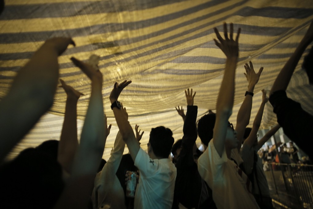 Protesters in Mong Kok support a canopy after heavy rain late Monday night. Photo: AP
