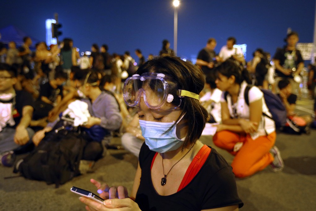 A student pro-democracy protester uses her smartphone as she and others sit outside Hong Kong's Chief Executive Leung Chun-ying's office on Sunday. Photo: AP