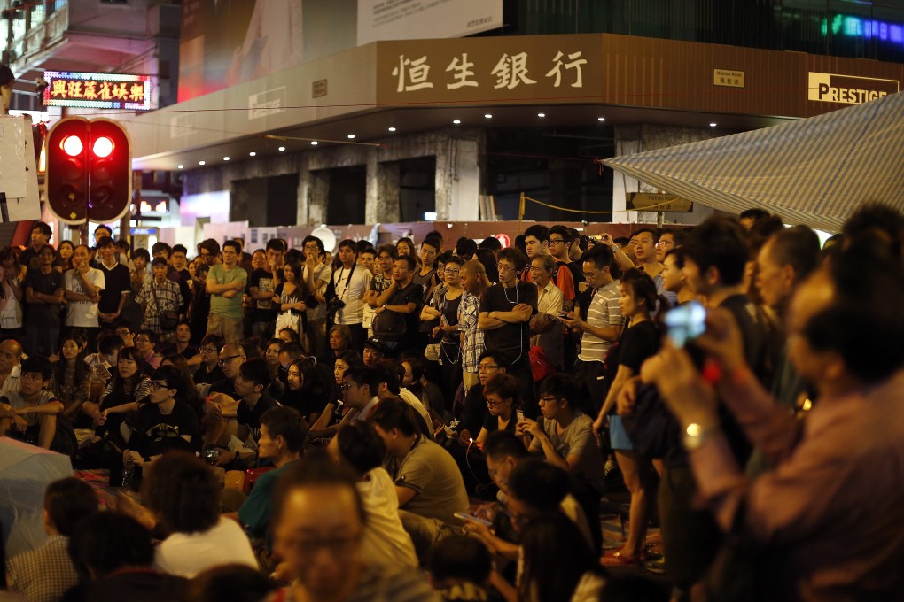 Pro-democracy protesters listen to a speech in Mong Kok during the ongoing Occupy Central mass civil disobedience campaign.