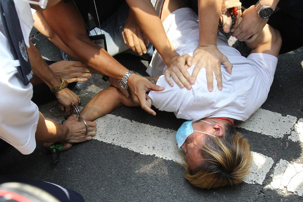 An anti-Occupy protester armed with a knife to cut the plastic cords that bound together barriers is arrested by police during the turmoil in Admiralty. Photo: Edward Wong