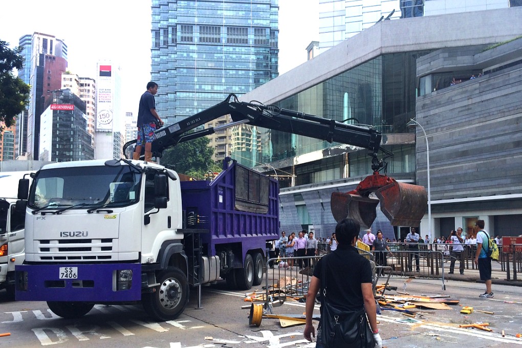 A crane is used to scoop up metal barriers and dump them into a truck in Admiralty. Photo: Jeffie Lam