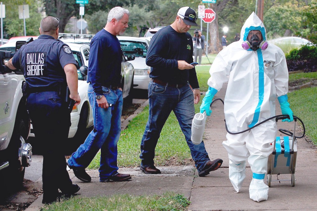 A man dressed in protective hazmat clothing leaves after treating the front porch and sidewalk of an apartment where a second person diagnosed with the Ebola virus resides