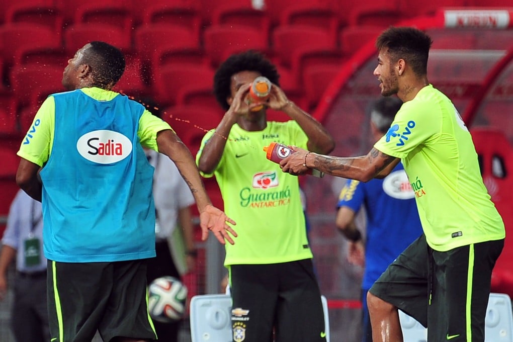 Neymar squirts liquid from a water bottle at a teammate during Brazil's training session in Singapore. Photo: Xinhua