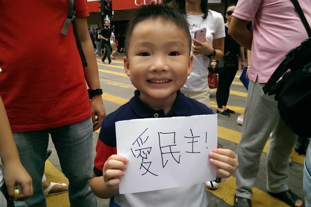 A little boy in the midst of Occupy Central holds up a sign saying "love democracy" in Chinese. Photo: SCMP Pictures