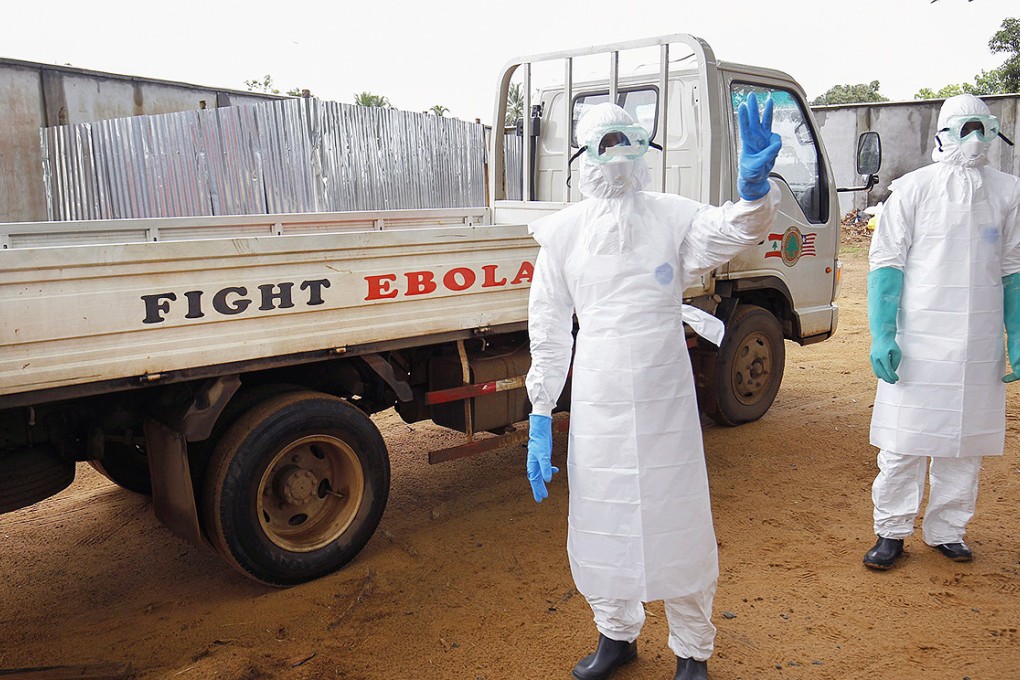 A health worker in a burial squad gestures with three fingers indicating three Ebola victims to be collected for cremation from a treatment centre in Liberia. Photo: EPA
