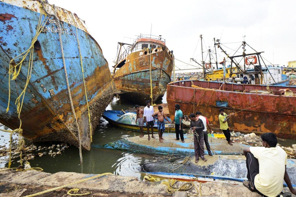 People stand on boats damaged by strong winds caused by Cyclone Hudhud in India. Photo: Reuters