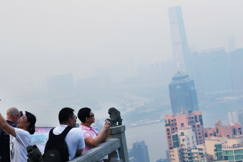 Tourists take photos on The Peak as smog shrouds Hong Kong. The city experienced its smoggiest days of the year in early June and mid-September. Photo: David Wong