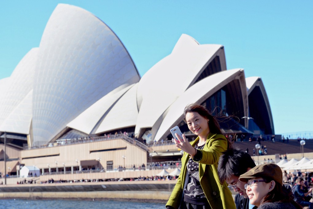 A tourist takes a "selfie" photograph in front of the Sydney Opera House in Sydney