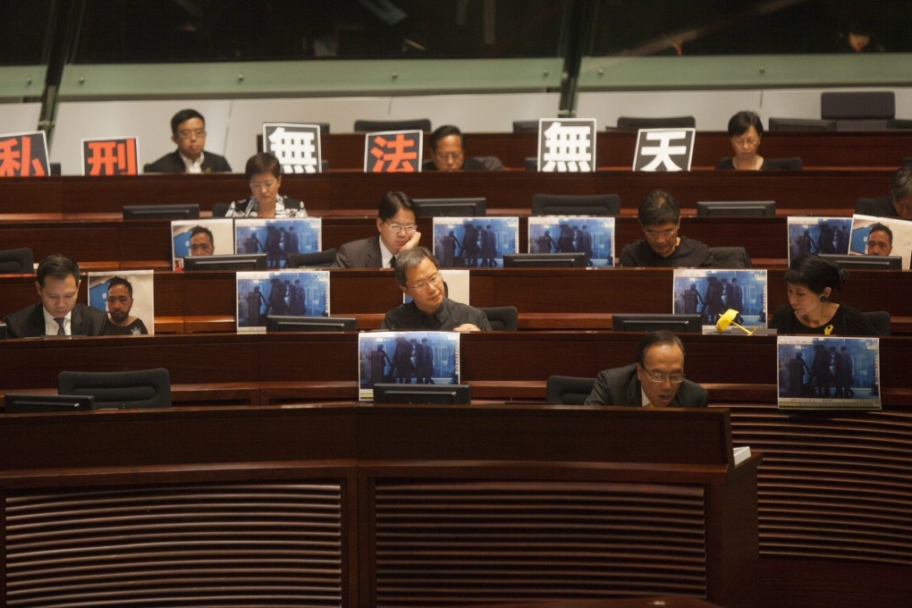 Pro-democracy lawmakers display posters of an unarmed social worker being beaten up in the dark by the Hong Kong police as Legco held its first meeting of the new session. Photo: EPA