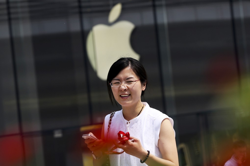 A woman holding an older version of an iPhone walks past an Apple store in Beijing. The iPhone 6 and 6 Plus models go on sale on the mainland at midnight. Photo: AP