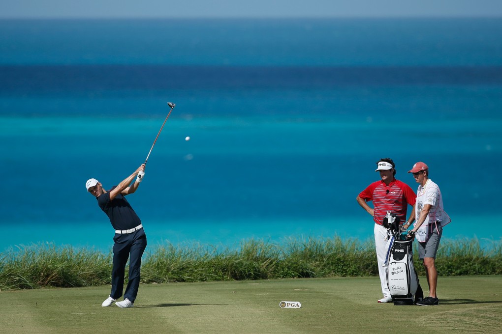 Martin Kaymer  hits his tee shot on the ninth hole as Bubba Watson  looks on. Photo: AFP