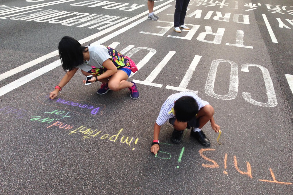 Students involved in a mobile democracy class write with chalk on the road during the Occupy protests.