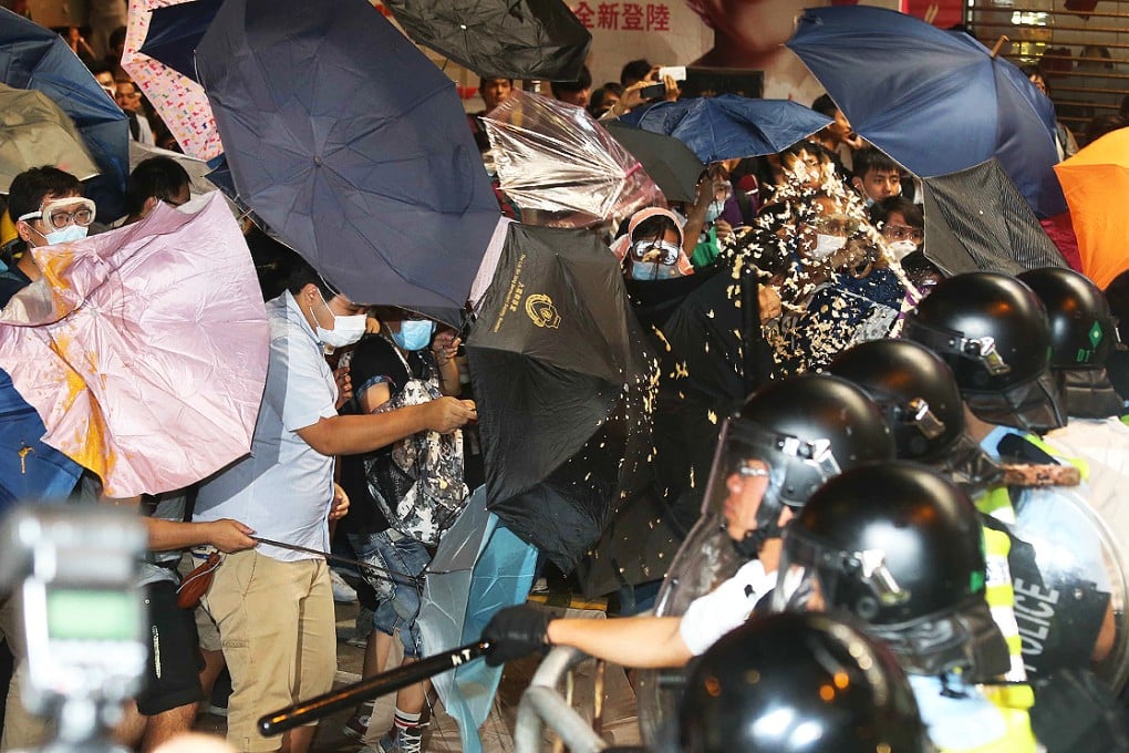 Protesters shield themselves with umbrellas as police fire pepper spray at the crowd. Photo: K.Y. Cheng