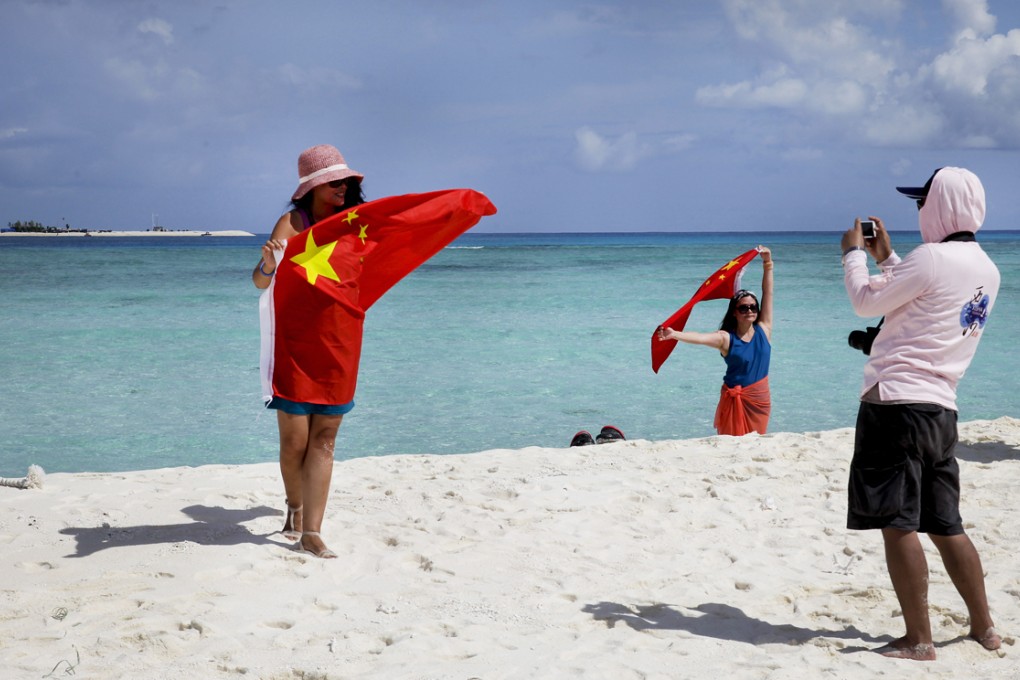 Tourists wave the national flag during a visit to Quanfu, an island in the west of the Paracels in the South China Sea, last month. Photo: AP